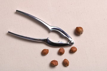 Metal nuts tongs and nut kernels chopped hazelnut shell mess up on a rough cloth cloth