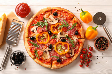 Delicious pizza and ingredients on white wooden background, top view