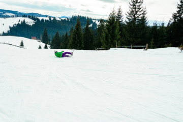 Fototapeta na wymiar Young man in green jacket and purple pants skiing.