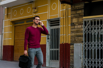 Young businessman is walking on the street while he is talking with his phone