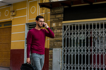 Young businessman is walking on the street while he is talking with his phone