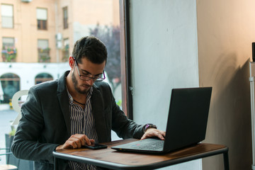 Young businessman in a pub working with his laptop