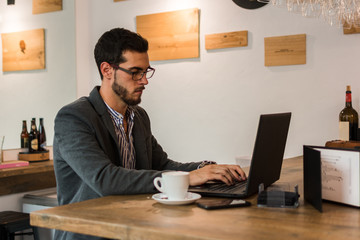 Young businessman in a pub working with his laptop