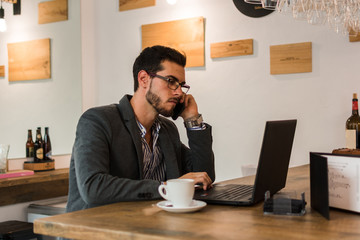 Young businessman in a pub working with his laptop