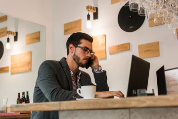 Young businessman in a pub working with his laptop