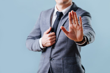 Businessman in suit making stop gesture, holding his palm outward over blue - obrazy, fototapety, plakaty