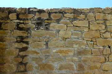 Old stone brick wall with blue sky above 