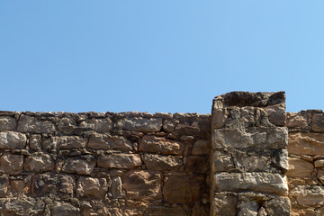 Stone wall of ruined old house with blue sky above 