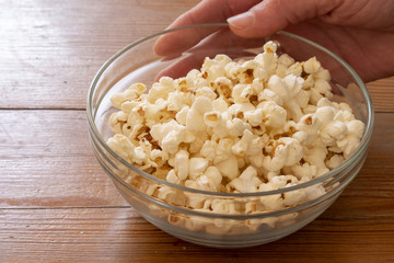 Bowl of popcorn, popped corn, healthy food on a wooden table.