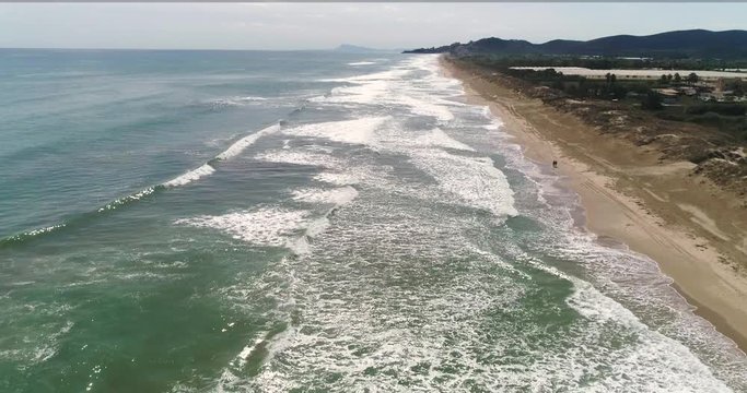 Vuelo de dron y vista general sobre amplia playa y grandes olas