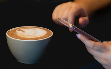 Close up of woman's hands holding mobile smart phone with a coffee in cafe