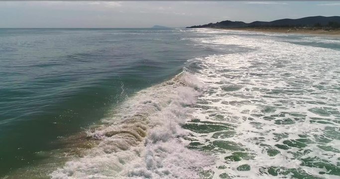 Seguimiento vuelo en paralelo de dron lateralmente de ola con espuma
