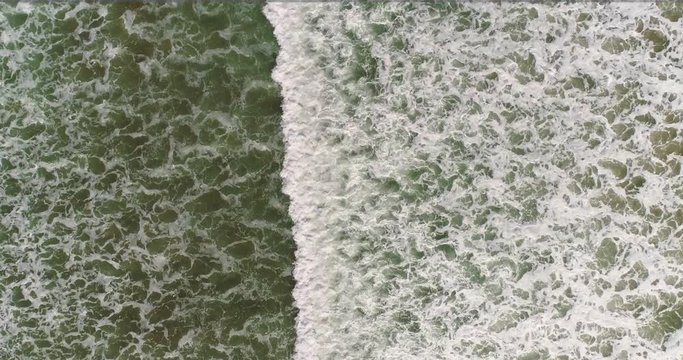 vista cenital de dron de olas con espuma en mar verde