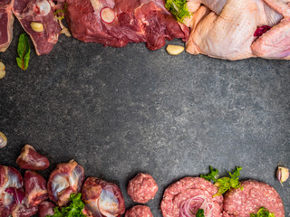 Assorted raw meat on dark background. Different types of meat and processed food. Top view, vintage toned image, blank space