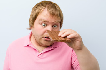 Caucasian crazy blond fat man holding a chocolate tablet