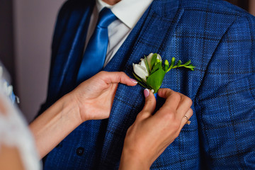 attach the boutonniere to the groom's suit