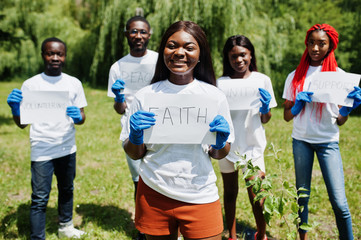 Group of happy african volunteers hold blank board with faith sign in park. Africa volunteering,...