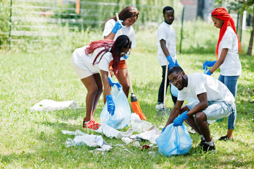 Group of happy african volunteers with garbage bags cleaning area in park. Africa volunteering,...