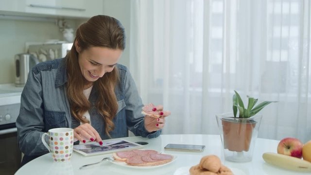 Woman using tablet at breakfast. Housewife having nutrition brunch at home.