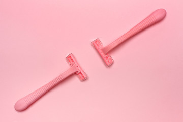 Two pink woman shaver opposite isolated on pink paper background. Copy space, place for text. Flat lay. Shaving concept.