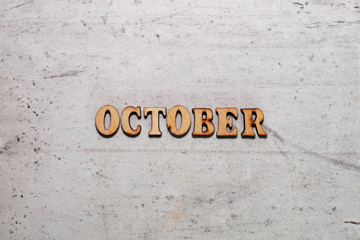 The word October laid out in wooden letters on a light background. Close-up. Summer time years and months of the year.