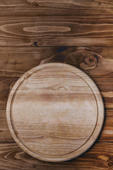 Empty blank pizza round cutting board on a wooden table. Place for text. Copy-space. Place for recipe. Pizza background. Top veiw, flat lay.