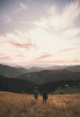 guy with girl in mountains go on sunset background