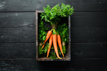 Fresh carrots on a black wooden background. Top view.