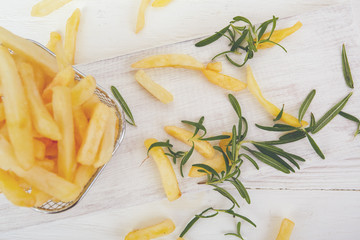 French fries with rosemary on a white wooden table.