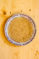 plate of raw dry rice on a light pine background. Groats on a wooden table.