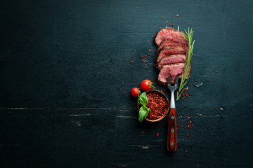 Beef steak on a fork. On a wooden background. Top view. Free space for your text.