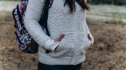 Women's hands in pockets of a white fluffy hoodie. The woman put her hands in her pockets to keep...