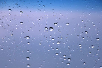 Rain drops with selective focus on transparent glass. Glass surface with water drops, violet toned....