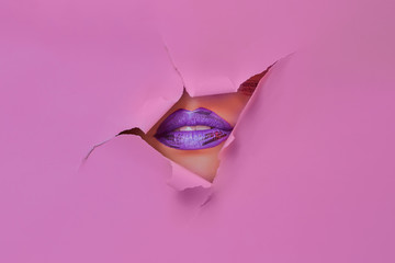 Woman lips in a pink paper hole