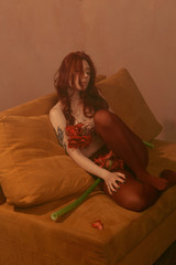 Fototapeta premium Beautiful girl with red hair, makeup and styling. Red flowers in the hands