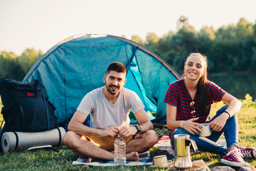 Naklejka na ściany i meble young happy couple camping together outdoor by the river