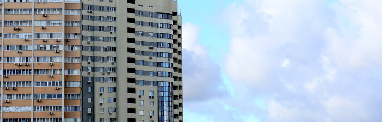 Fototapeta premium High-rise building on a background of blue sky with clouds. Horizontal photography. Concept - urban development.