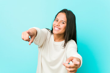 Young pretty hispanic woman cheerful smiles pointing to front.