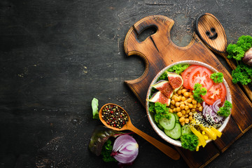 Healthy vegetable buddha bowl lunch with chickpeas, figs, cucumber, tomatoes and onions. Dishes menu. Free copy space. Top view.