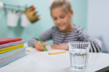 little school girl sitting desk at her room and drinking water