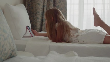 Girl Look Phone Lie Swing Legs Bedroom Background. Caucasian Female Teenager Browse Smartphone Comfortable Bed. Long Hair Child Hold Mobile White Cushions Design Interior Covers Leisure Activity