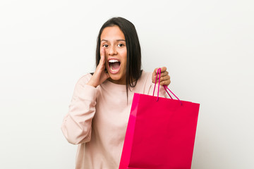 Fototapeta na wymiar Young hispanic woman holding a shopping bag shouting excited to front.