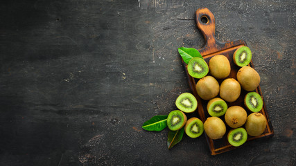 Fresh kiwi and green leaves on the table. Rustic style. Fruits. Top view. Free space for text.