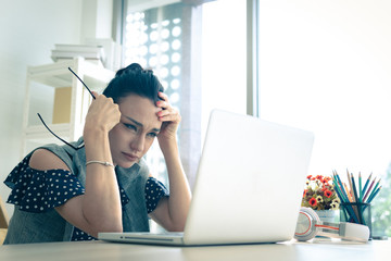 Woman feels frustrated while looking at laptop. Online social bullying and online bad news message.