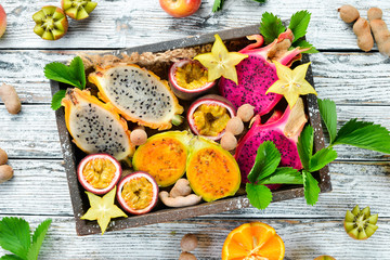Tropical fruits - Maracuya, pineapple, dragon fruit, kiwi and cactus on a white background. Top view. Free space for text.