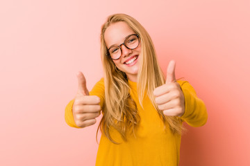 Adorable teenager woman with thumbs ups, cheers about something, support and respect concept.
