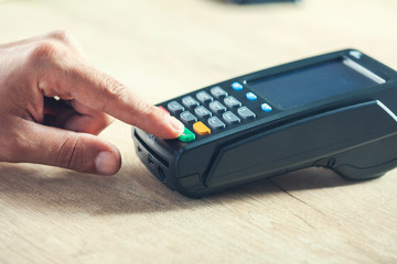 man hand payment terminal on desk