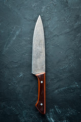 Kitchen old knife on a black stone table. Top view. Free space for your text.