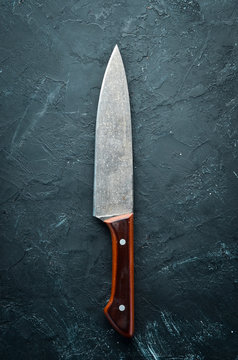 Kitchen old knife on a black stone table. Top view. Free space for your text.