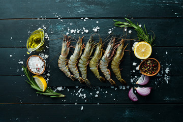 Raw black tiger prawns with lemon. Seafood. Top view. On a black background. Free copy space.